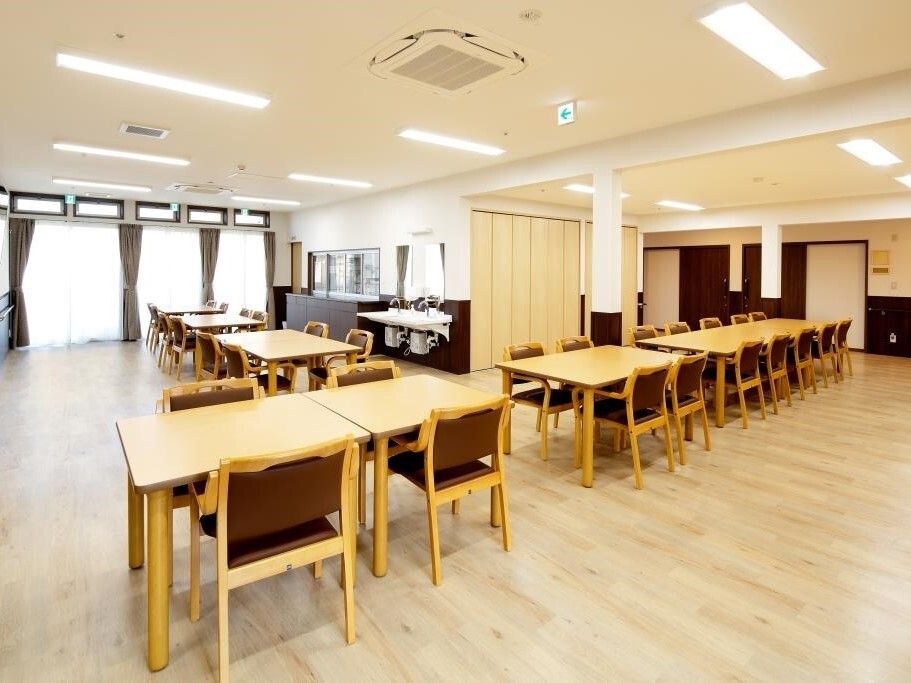 木製のダイニングテーブルセットが複数置かれた食堂には大きな窓があり、車いす対応の洗面所もある。