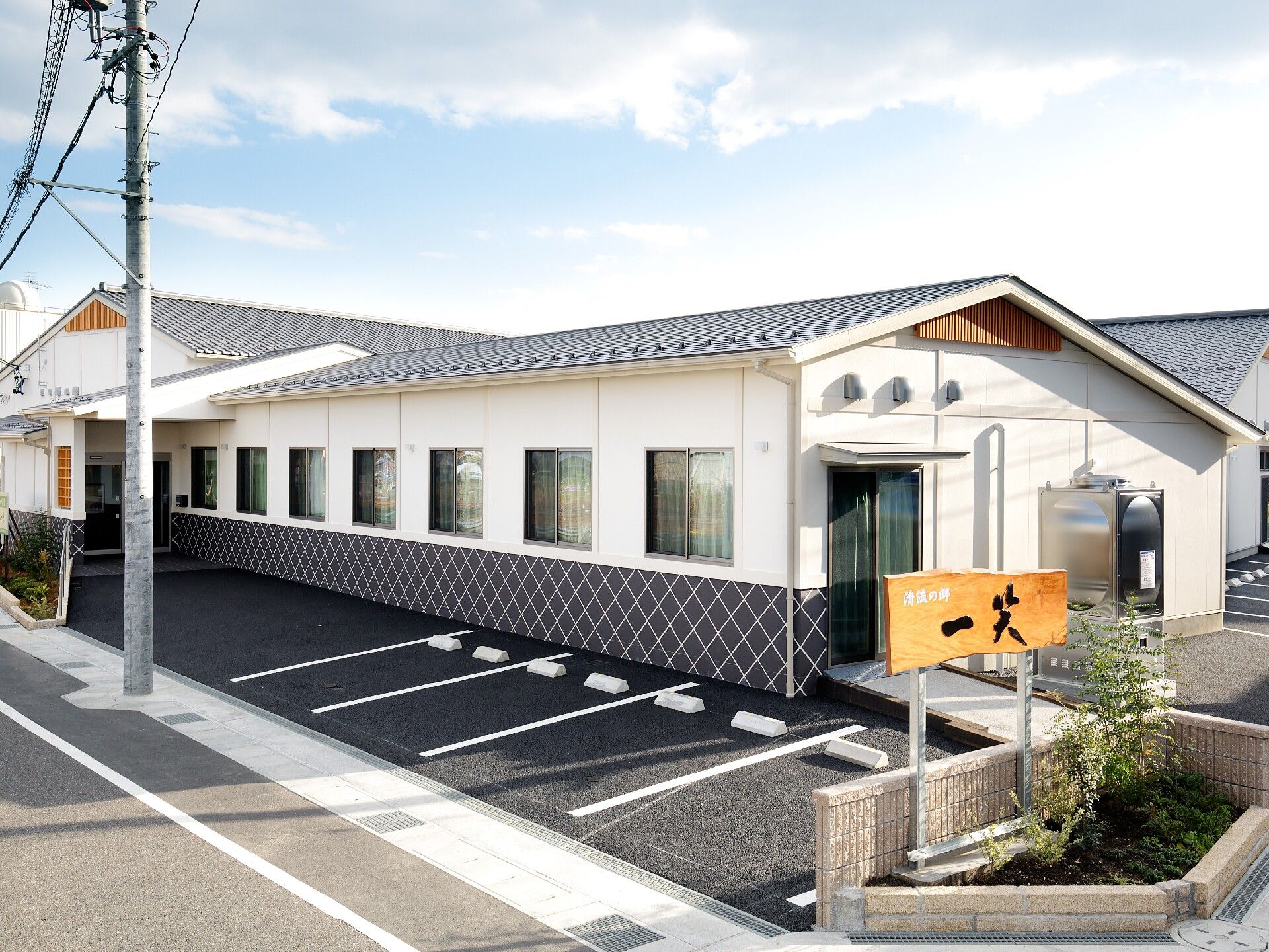 駐車場がある敷地内には平屋建ての純和風の建物があり、木製の館銘板が建っている。
