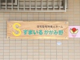 ホーム名が書かれている大きな木製の表札が設置されているベージュの外壁。
