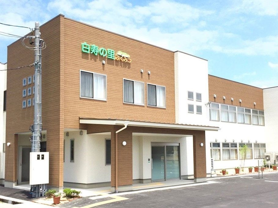 2階建ての建物。ブラウンと白で玄関には屋根も付いている。