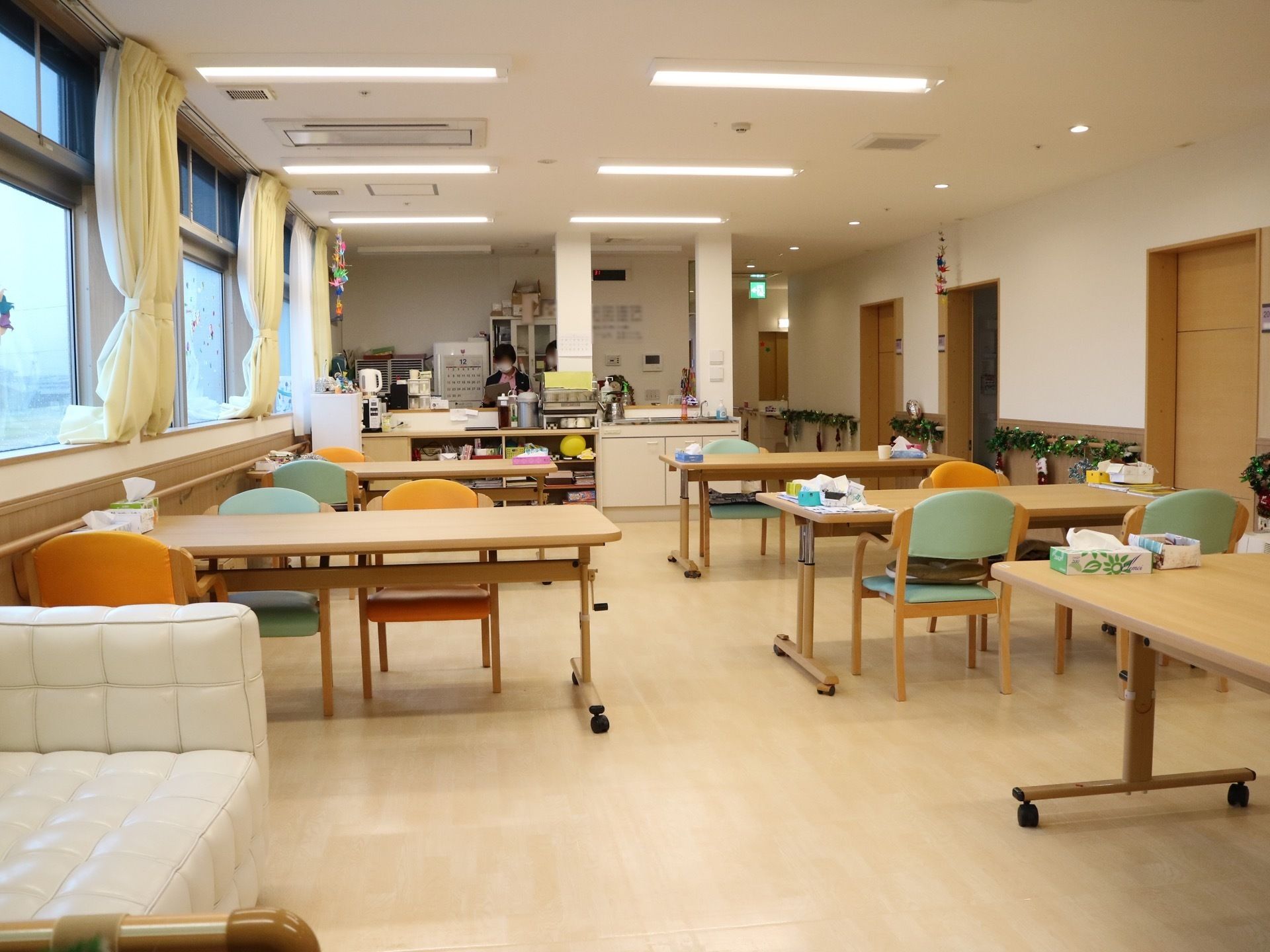キャスター付きダイニングテーブルが５つ置かれ、９脚の椅子がセットされている。流し台が設置されている。