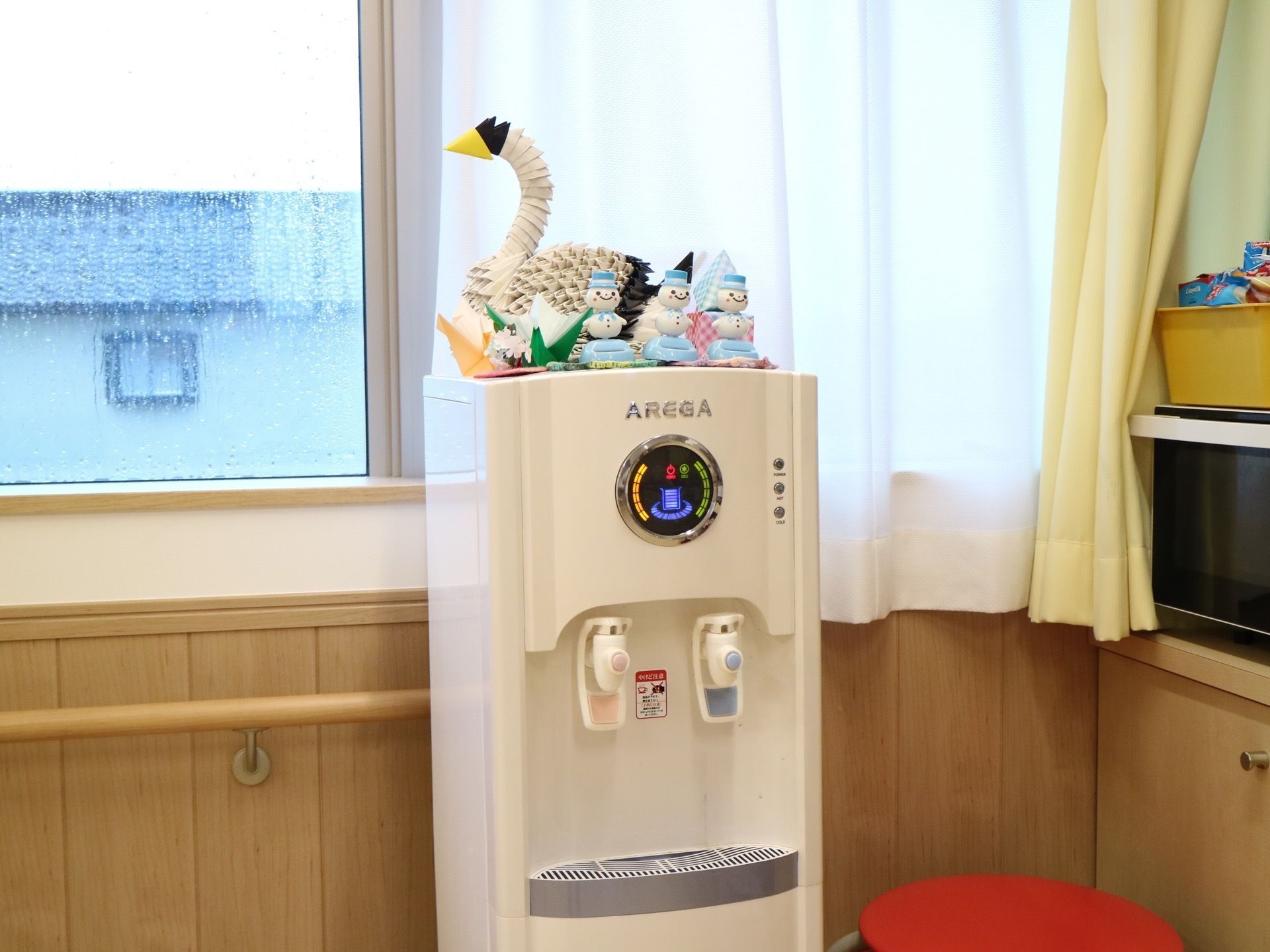 丸いインジケーターの付いた淡いベージュ色の給水器が設置されている。その上には手作り鳥や雪だるまが飾られている。