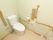 折り畳み式、固定式のものなど、手すりがたくさん設置されたトイレである。壁には温水洗浄便座のスイッチがある。