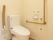 最新型の温水洗浄便座が設置されたトイレである。便座の右側には折り畳み式の手すりが取りつけられている。