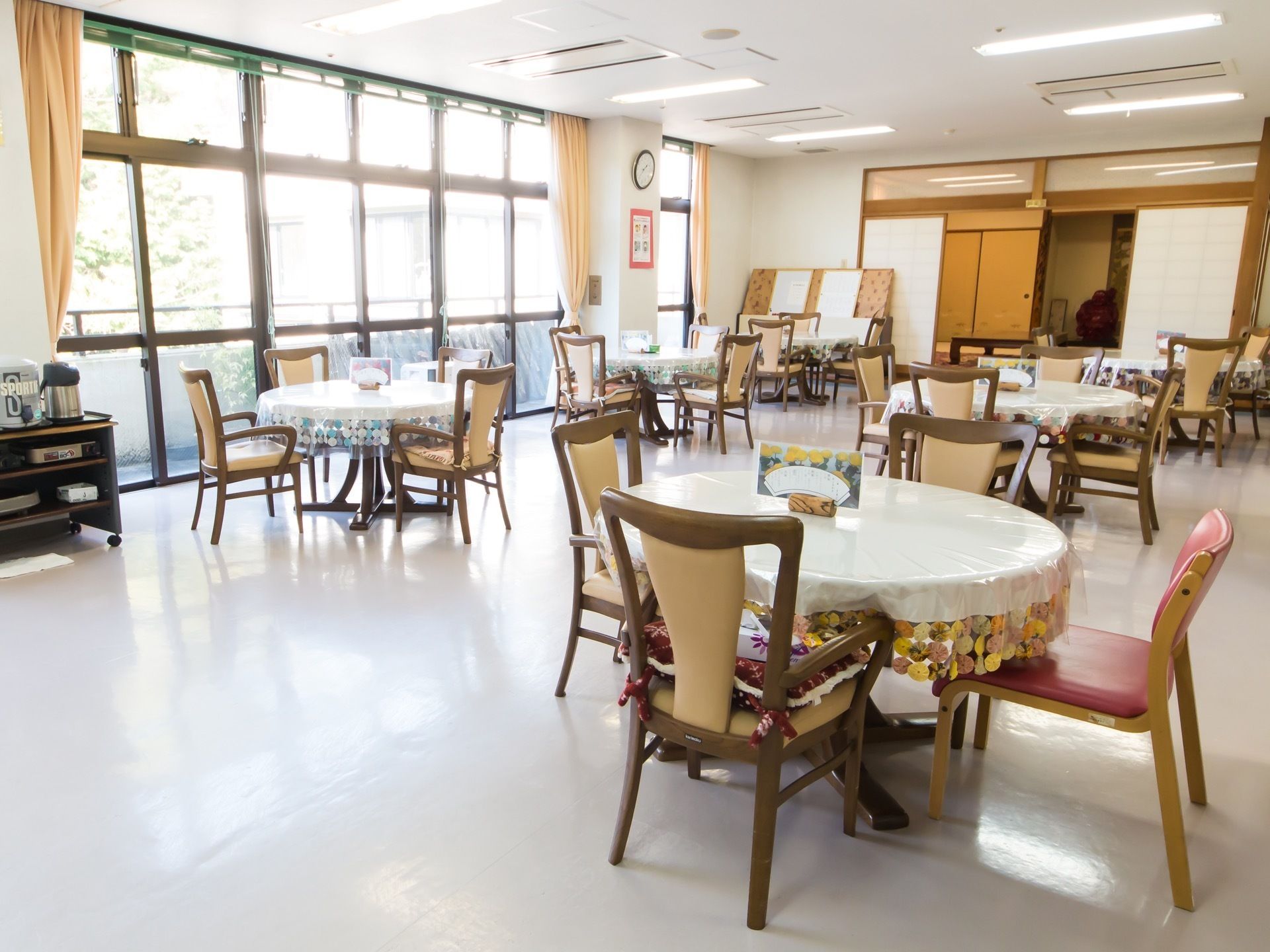 食堂に、丸テーブルが６台、間隔を空けて置かれている。奥には、障子で仕切られた和風の休憩スペースがある。