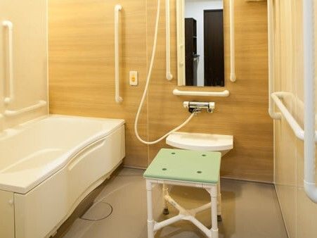 白を基調とした浴室の一面の壁が木目調で穏やかな雰囲気。スタッフにつながる呼び出しボタンもある。