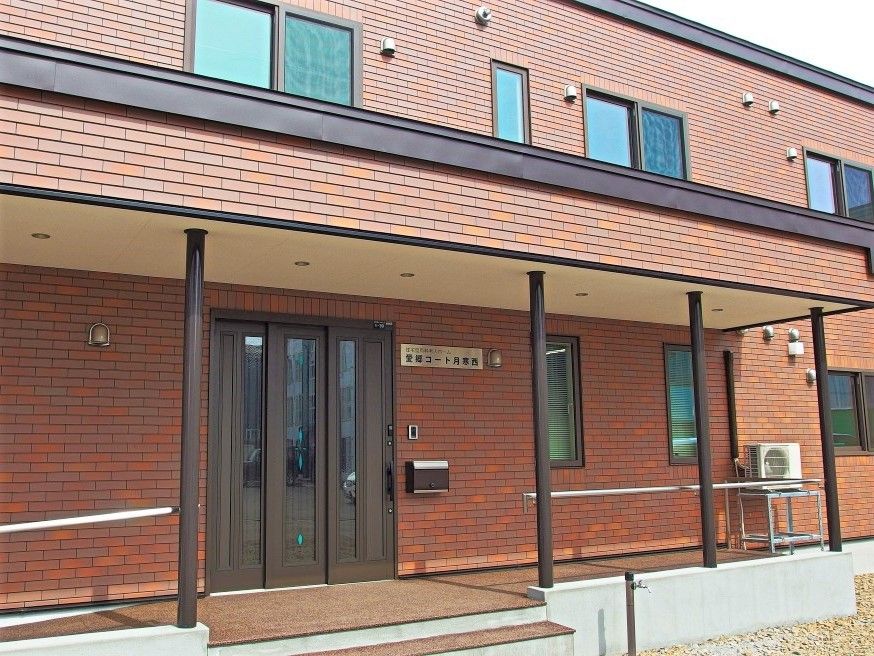 横に長い２階建ての建物の外観。入り口付近にスロープが付いている様子がわかる
