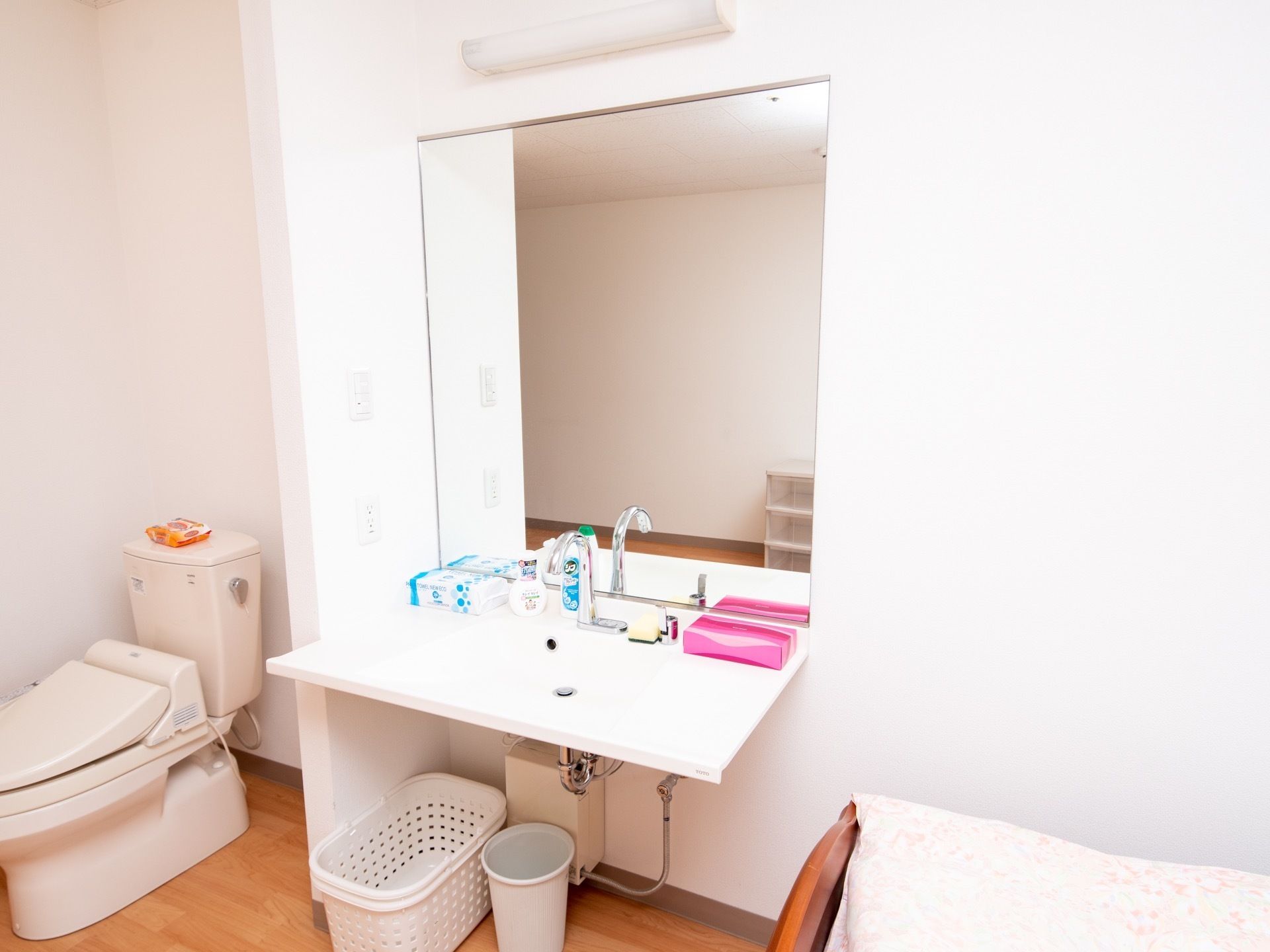 居室にある洗面台。すぐ側にはトイレがある。壁には鏡が設置され、洗面台の周囲は広く物が置けるようになっている。