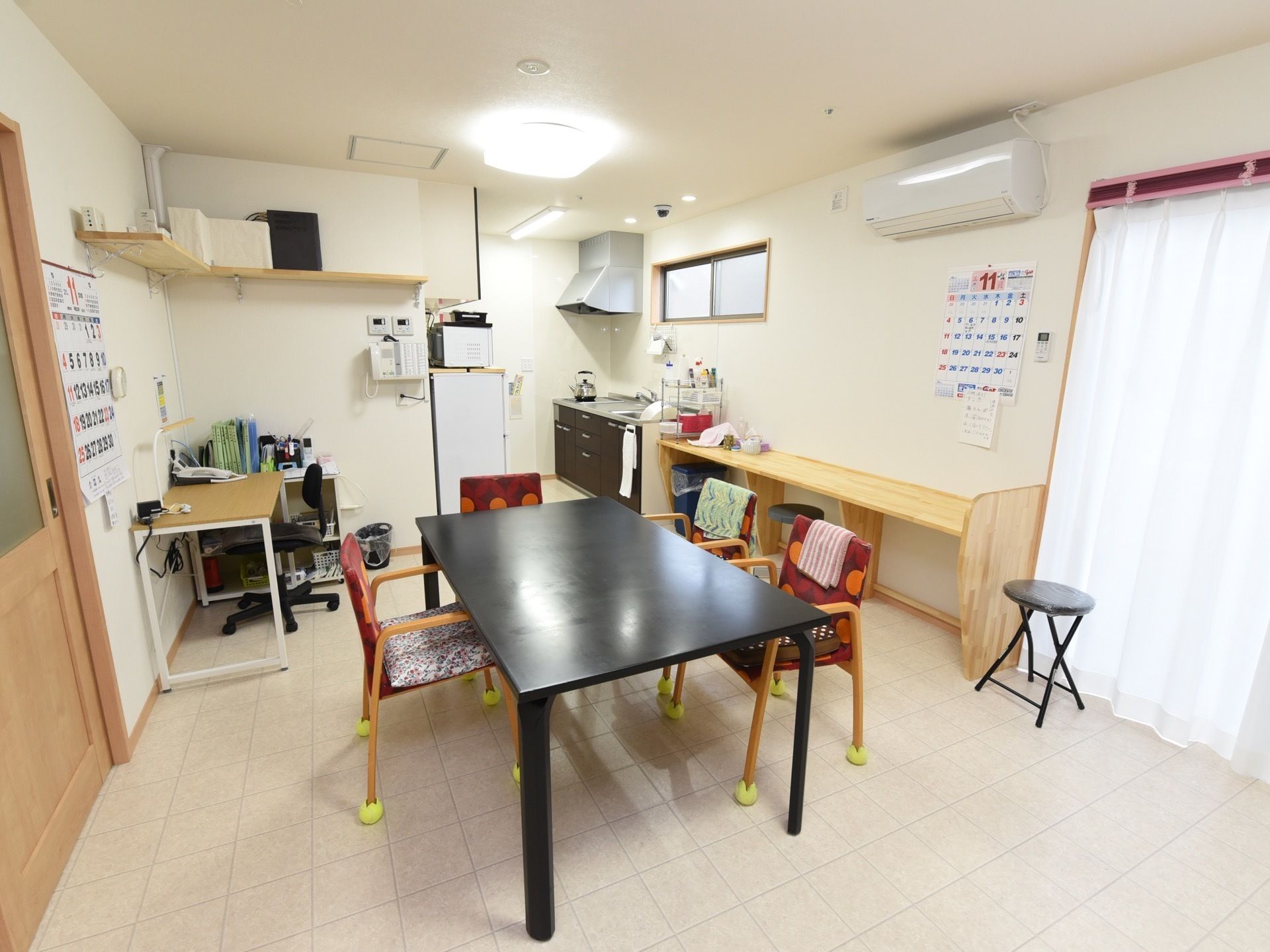 広々とした明るいスタッフルームである。事務机とテーブルセットが置かれ、キッチン、冷蔵庫、電子レンジ、エアコンが完備されている。