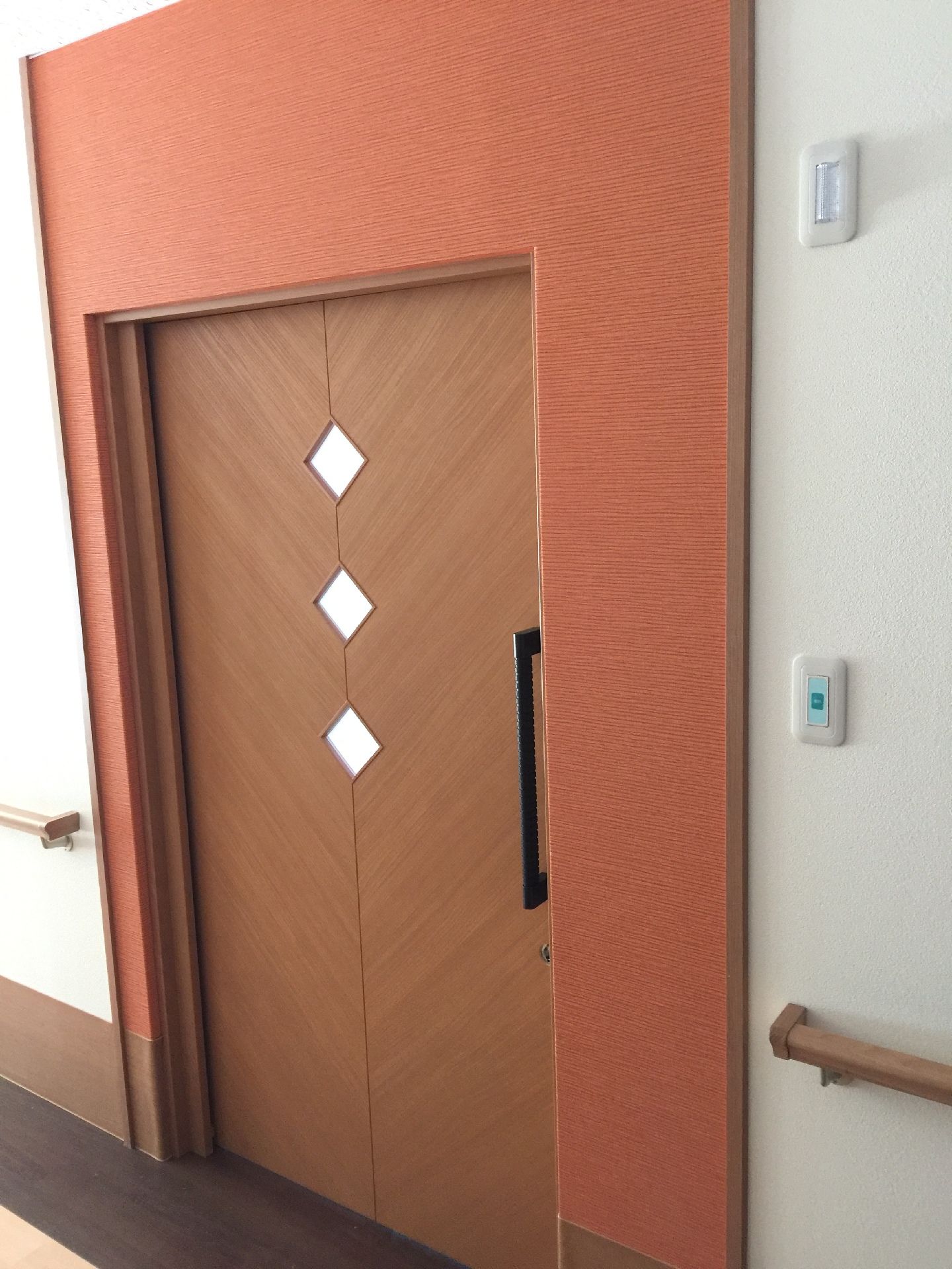 居室のドアはおしゃれな引き戸で、ドアの周りには赤い壁があり色で識別できるようになっている。