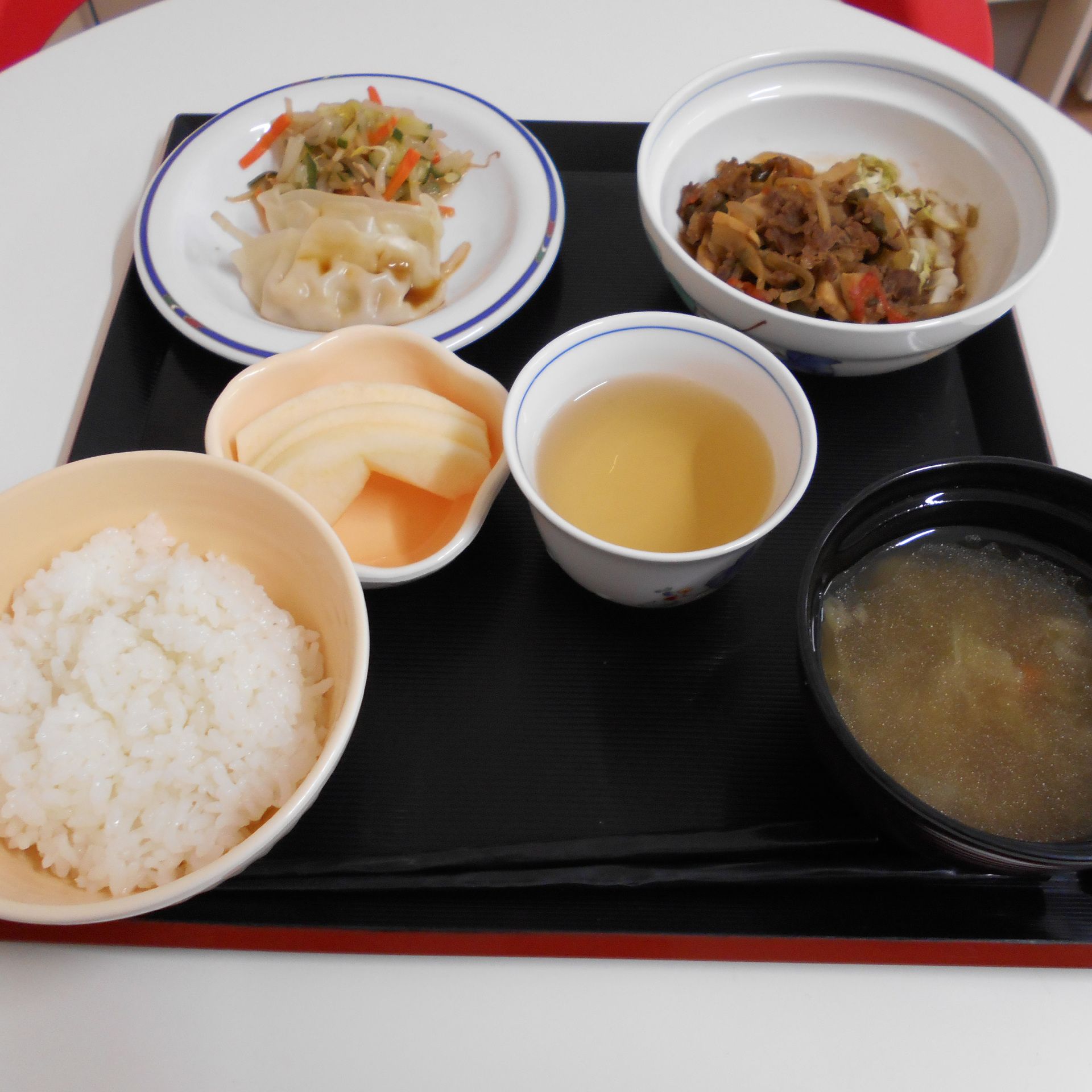 餃子や煮物、ご飯と味噌汁とリンゴのデザートが付いたメニュー