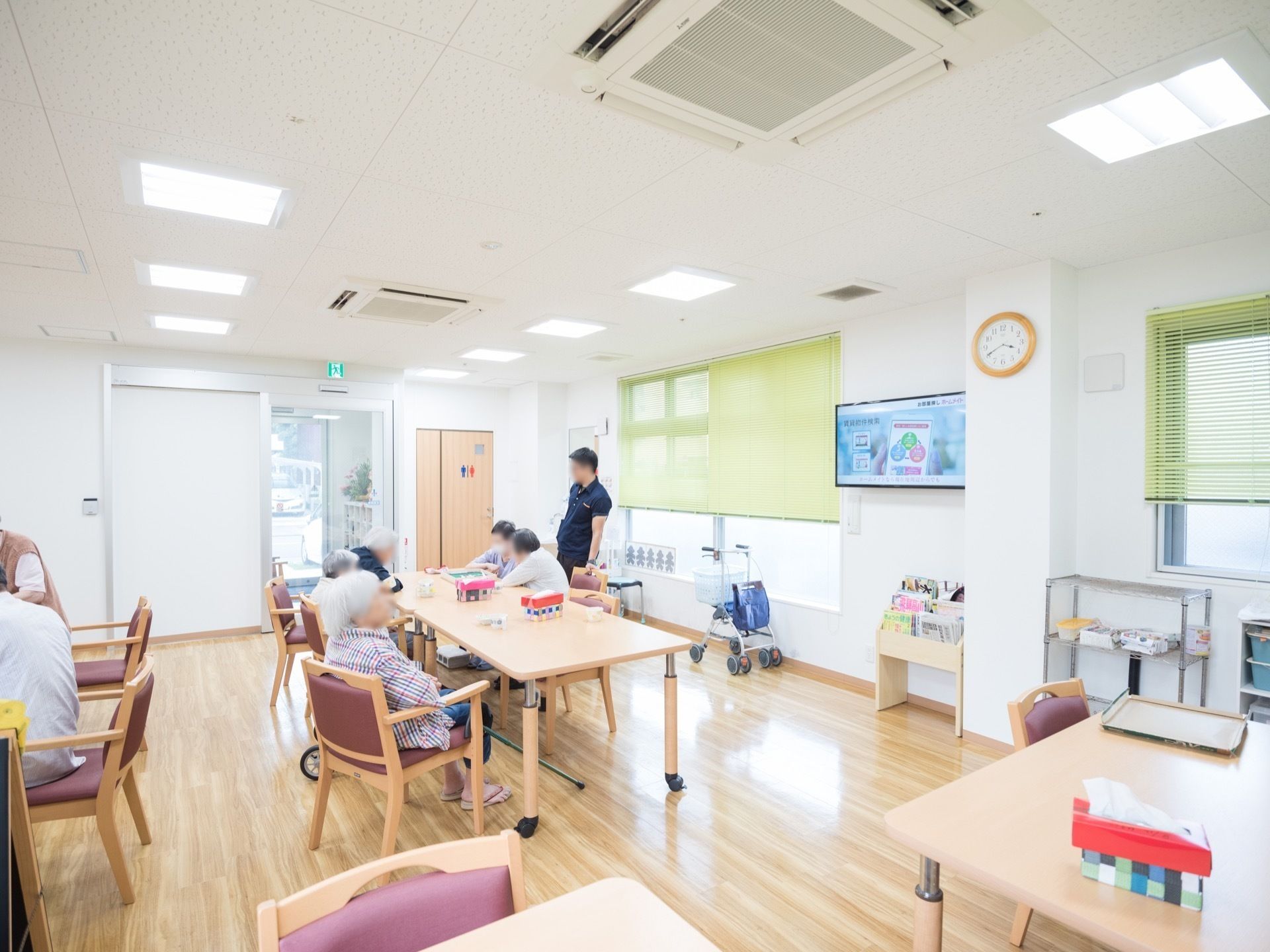 白い内装とフローリングであたたかみがあり、右壁面にテレビがある食堂