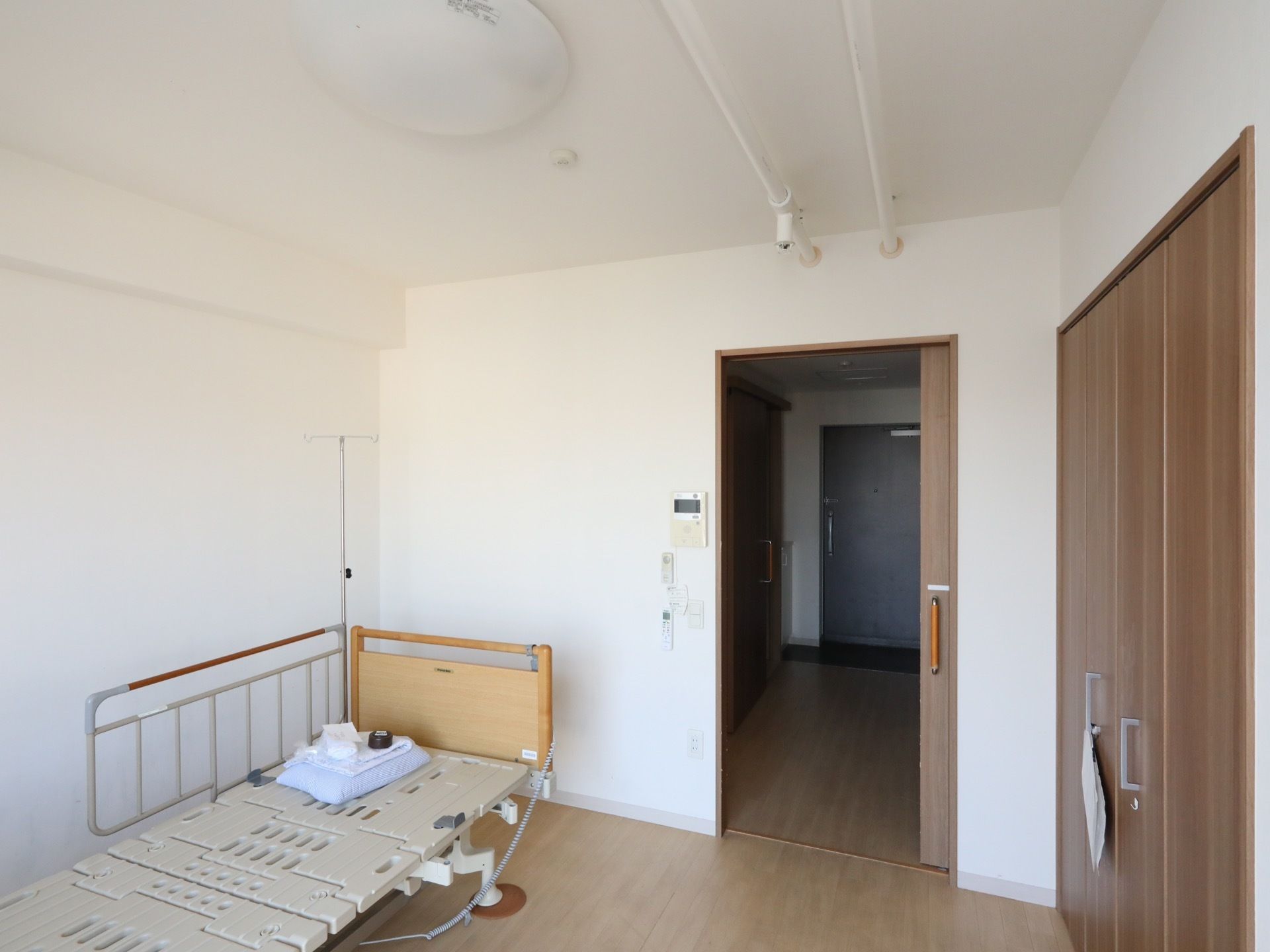 フローリングの居室に、介護用ベッドが１台置かれている。ベッドの向かいには備え付けのクローゼットがある。