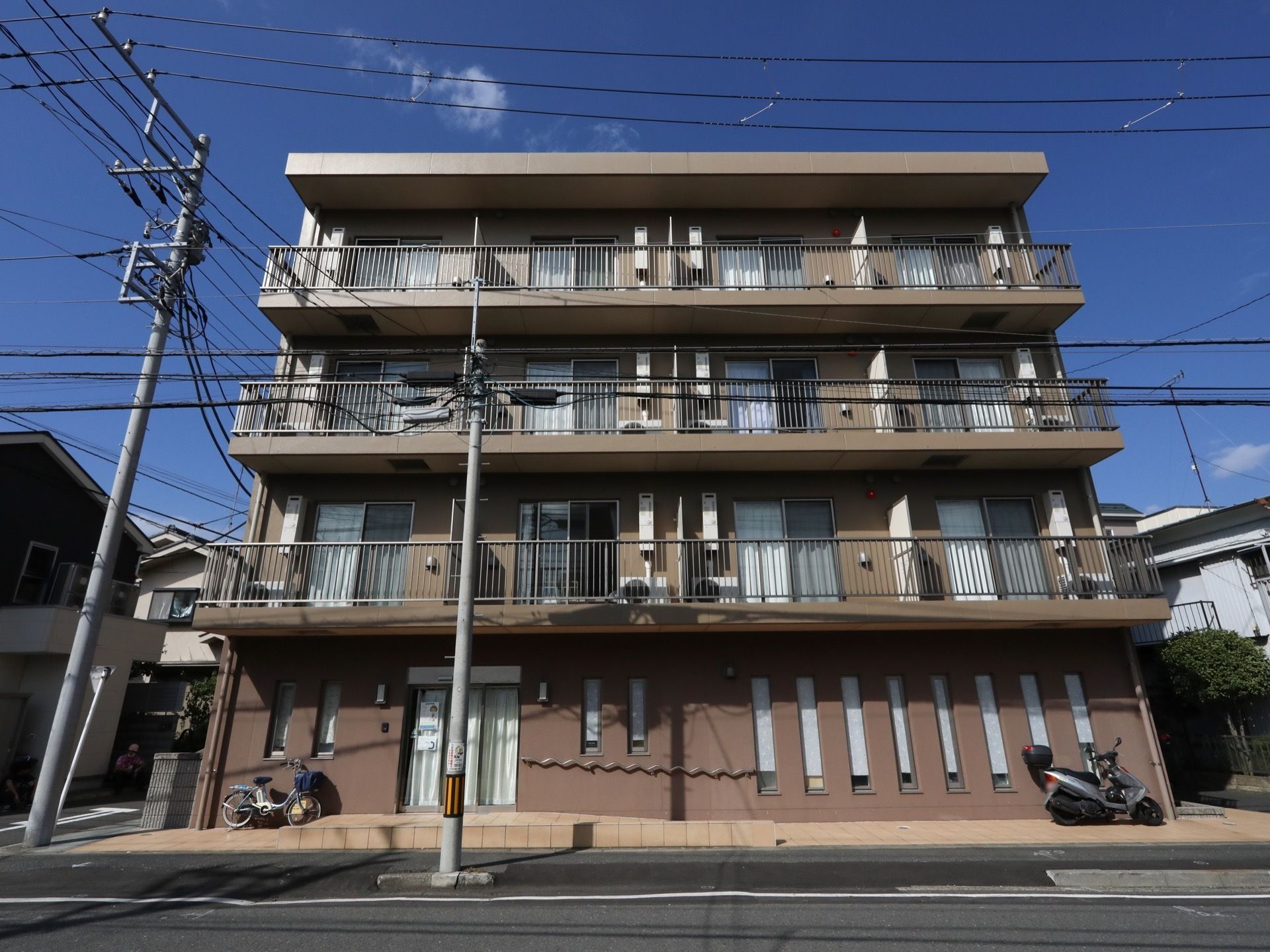 通り沿いに４階建ての住宅が建っている。居室にはベランダが付いていて、日当たりの良い造りになっている。