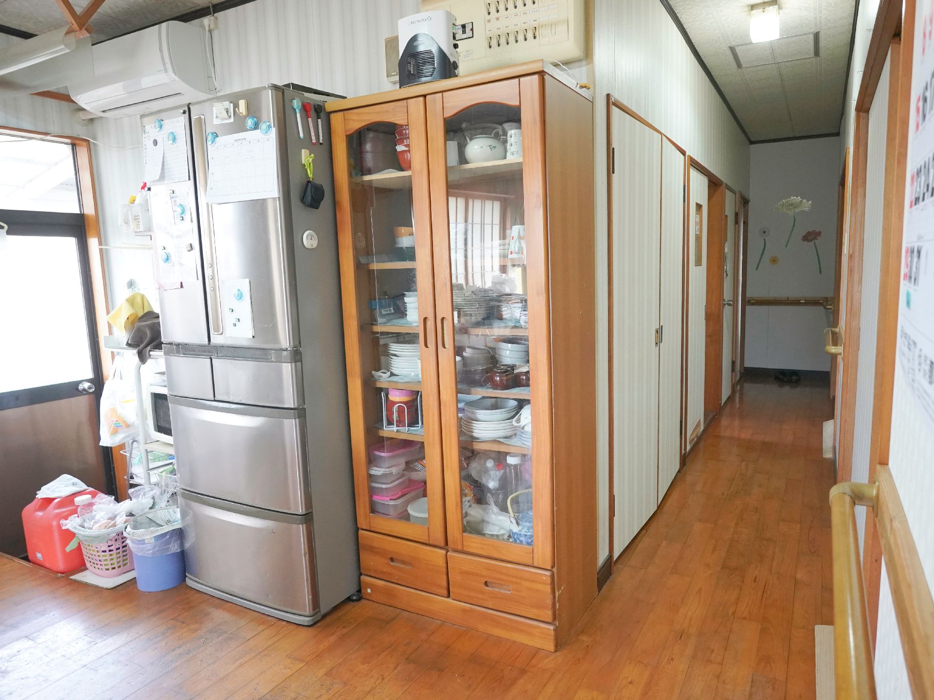 緑の多い屋外で笑顔で過ごしている車いすの高齢女性。そばには男性スタッフが笑顔で寄り添っている。