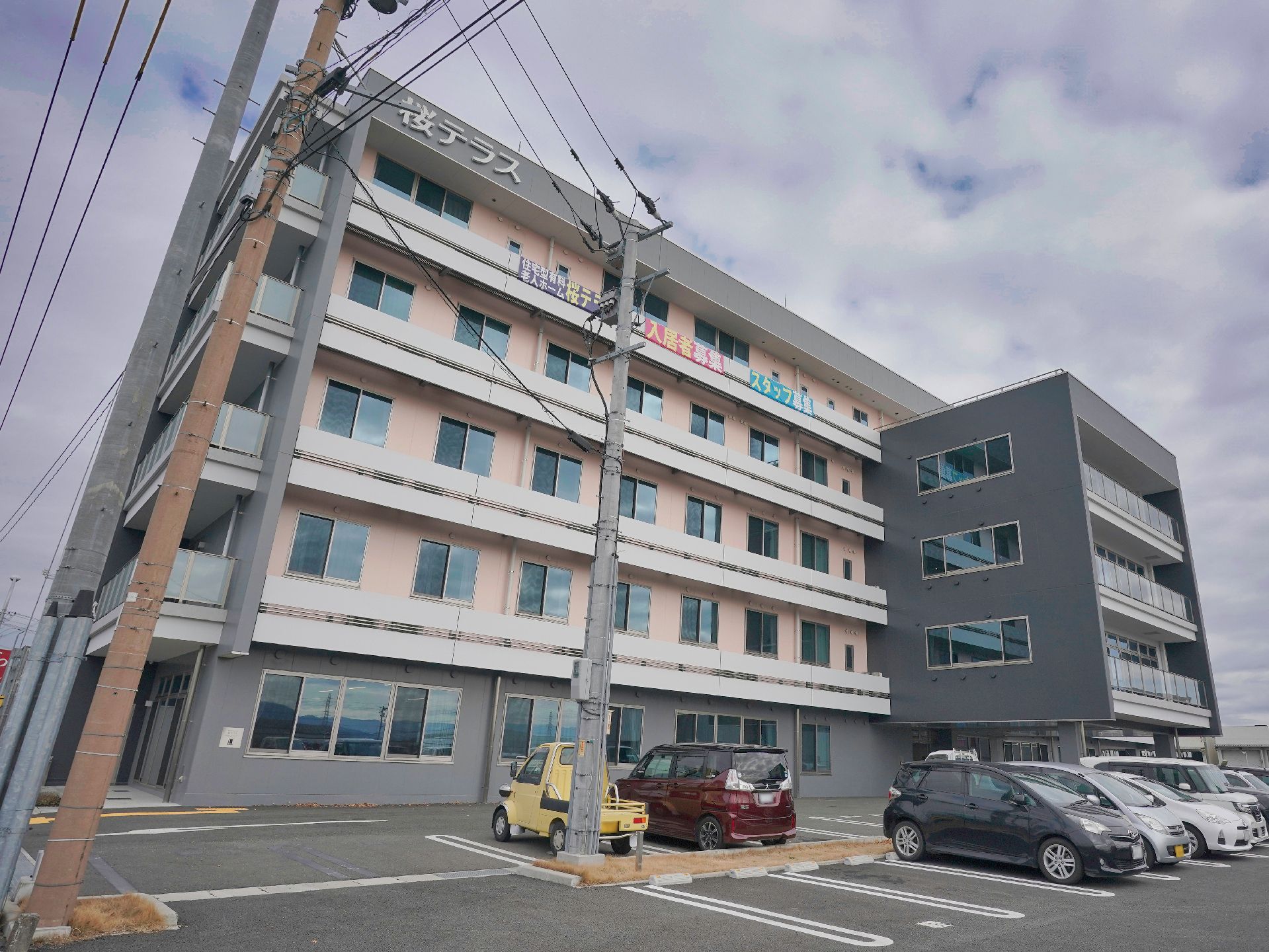 白い服を着た高齢女性とブルーのユニフォームを着た男性スタッフが並んで体操をしている。