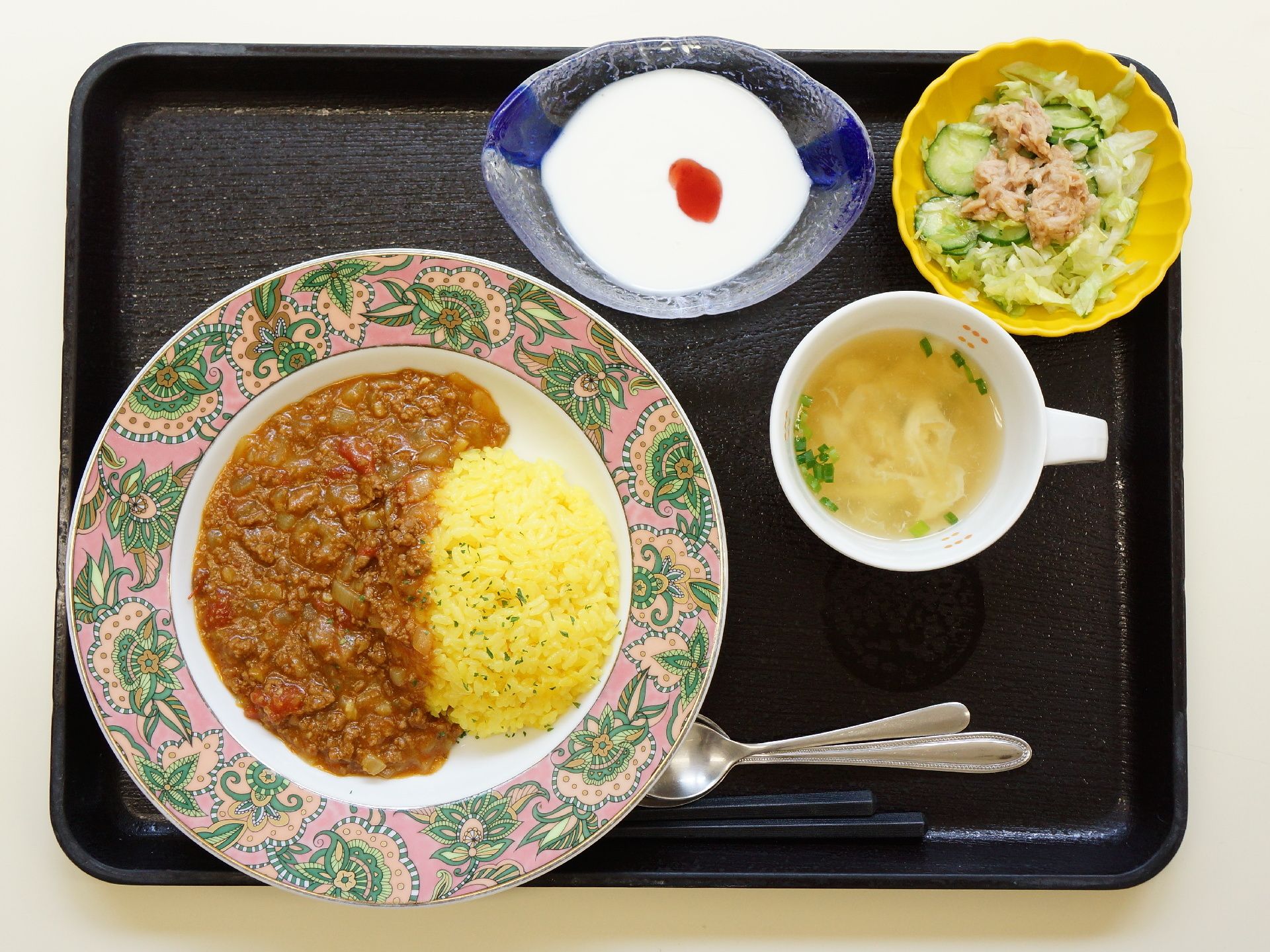 黒塗りのお盆に乗せられたある日の料理。カレー、スープ、お浸し、ヨーグルトと栄養バランスが考えられたメニューである。