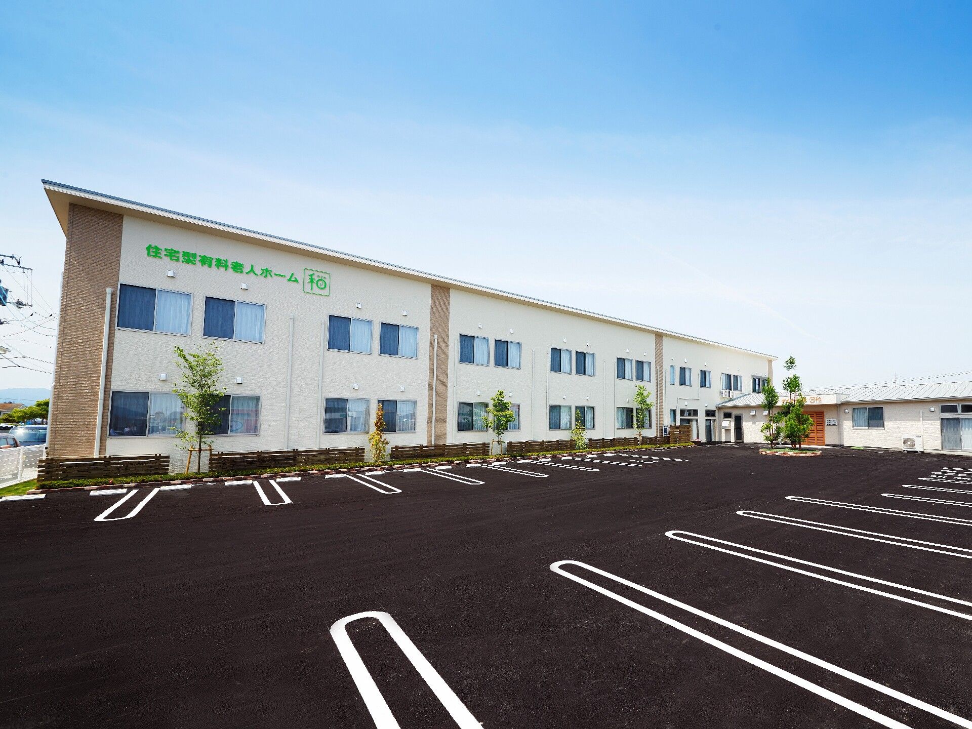グリーンの文字でホーム名が書かれた２階建ての建物。ベージュとブラウンで落ち着いた雰囲気。