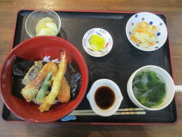 唐揚げに野菜が添えられた皿に小鉢にスープ、デザートが付いた食事例