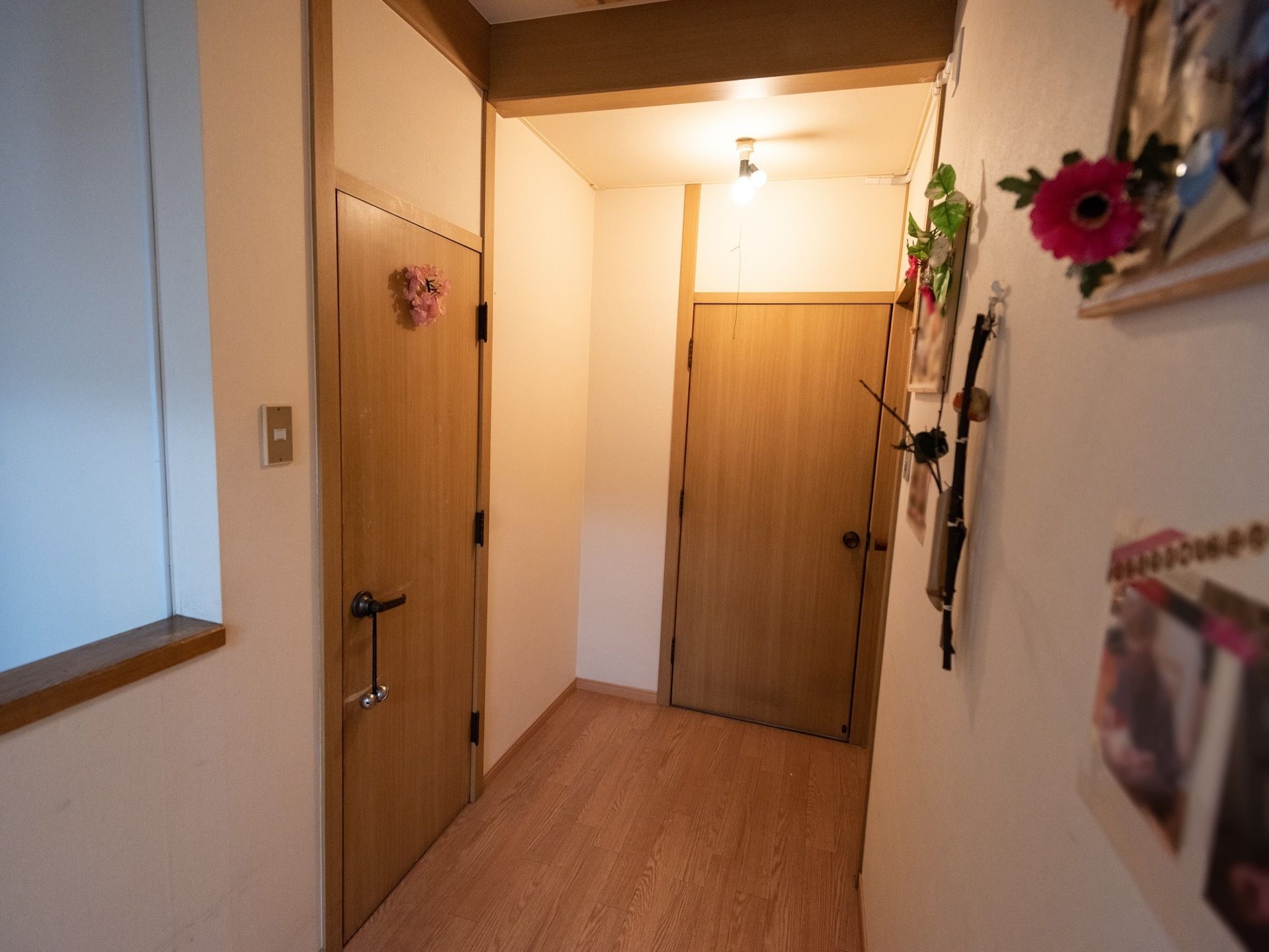 通路にある各部屋の扉は、木目調となっている。天井には照明器具があって、壁にスイッチが取り付けられている。