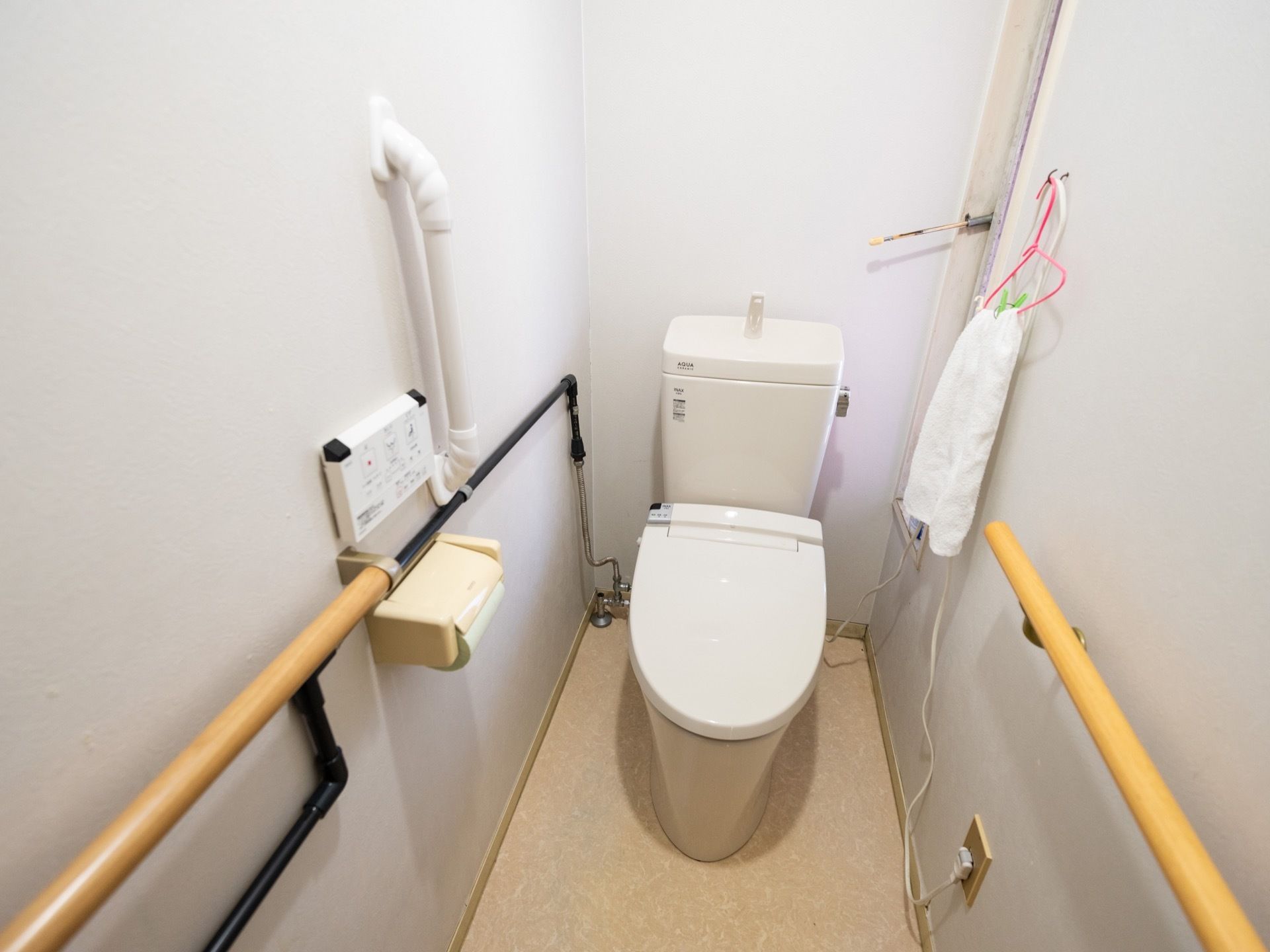 トイレの壁には手すりがあり、操作パネルが取り付けられている。洋式便器には、温水洗浄便座を設置している。