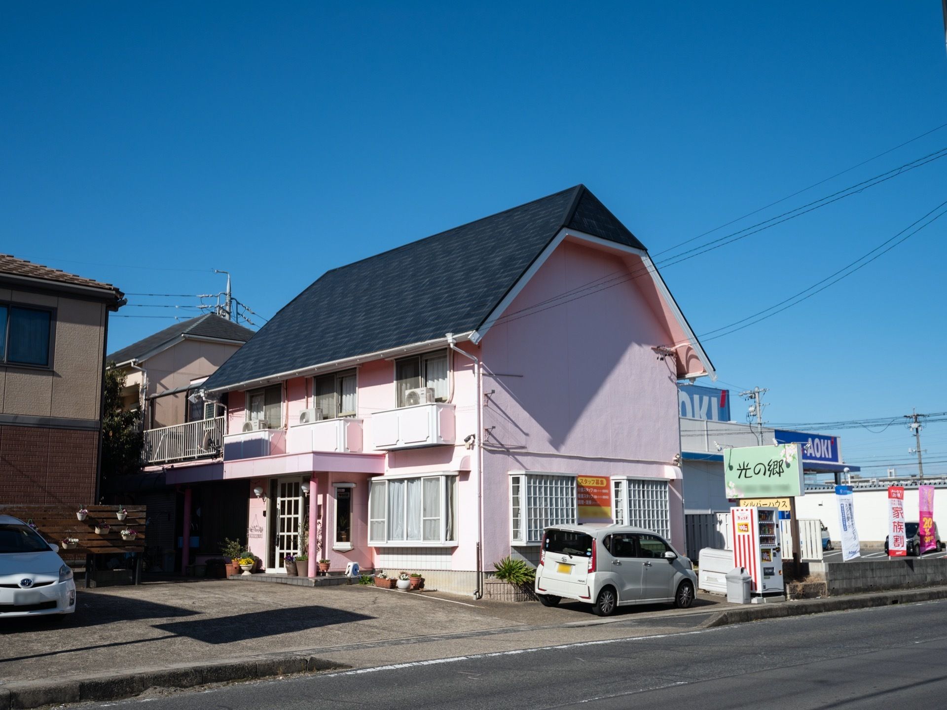 広々とした敷地には、駐車スペースが確保されている。大きな看板の下には、ドリンクの自動販売機が置かれている。