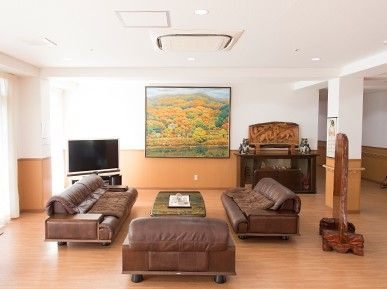 ブラウンの革張りのソファセットが中央に置かれ、周辺にはテレビや絵画などが飾られたスペース。