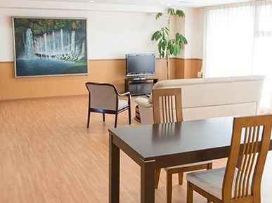 大きな窓が付き、ソファやいすがテレビの周りに置かれ、テーブルセットもある。