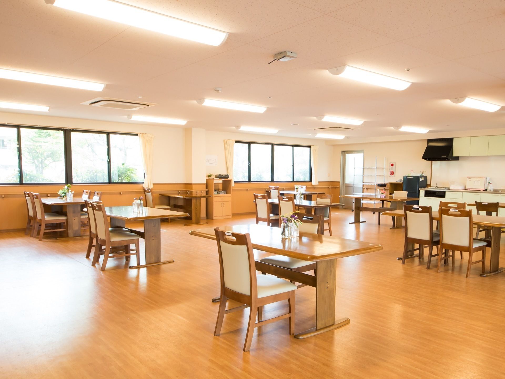 食堂の天井には照明がたくさんついている。テーブルがひとつずつ置かれている。奥の壁際にキッチンがある。