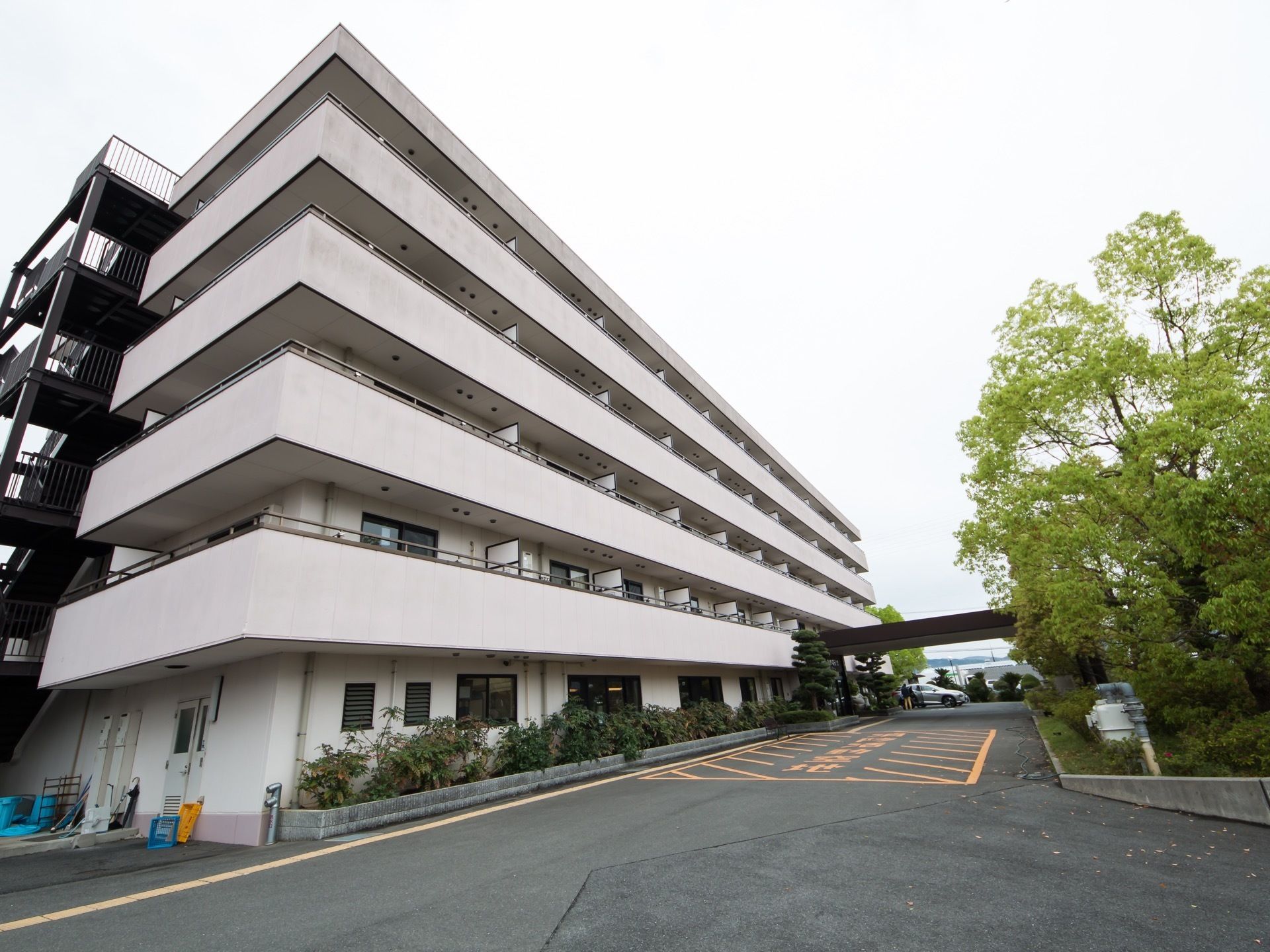 白色と薄いピンク色を基調とした５階建ての施設である。玄関前には車寄せがある。柵がついた外階段が設置されている。