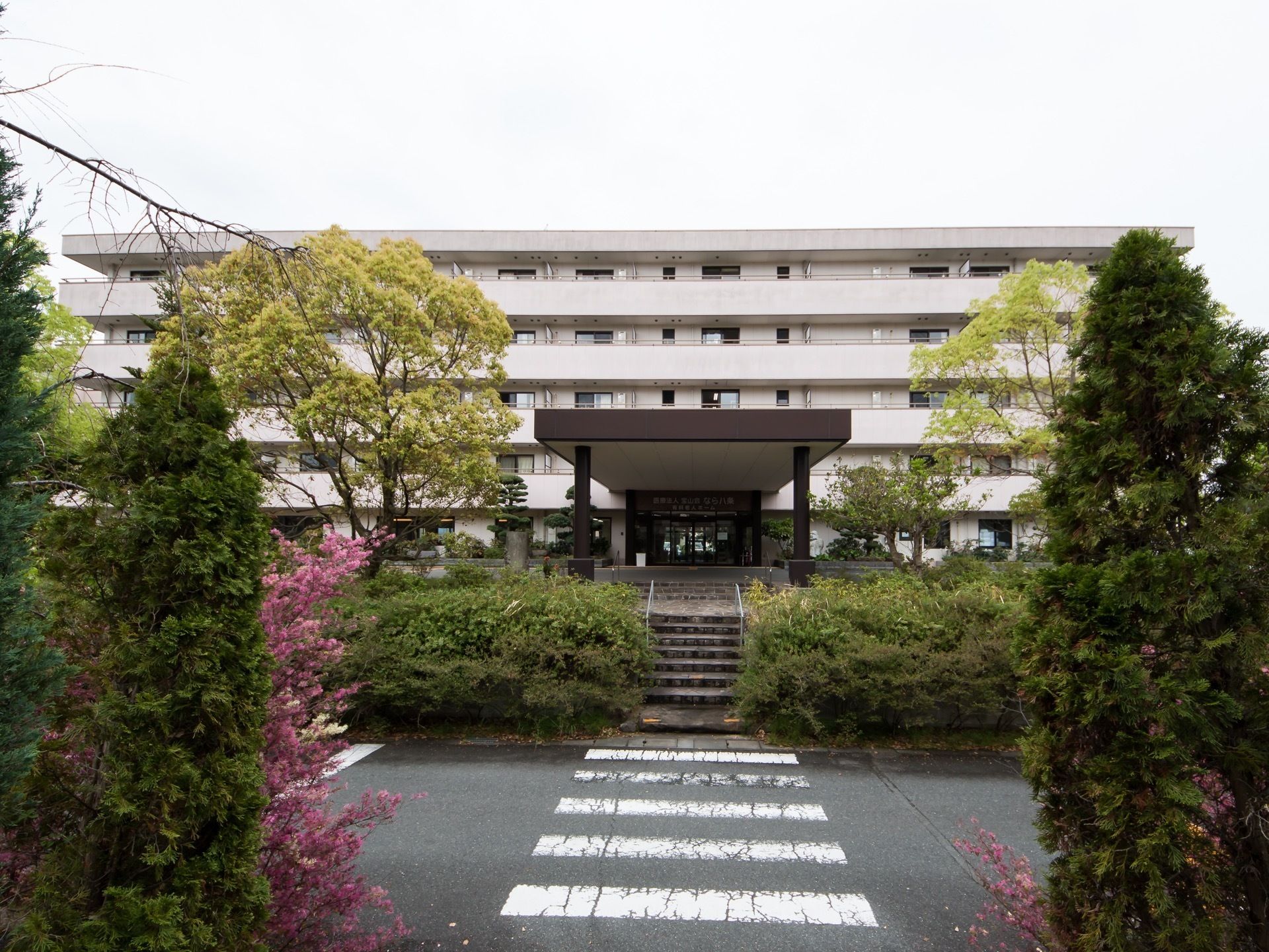玄関には大きな車寄せがある。玄関前には階段があり、道路面に下りることができるようになっている。いろいろな木々が生えている。