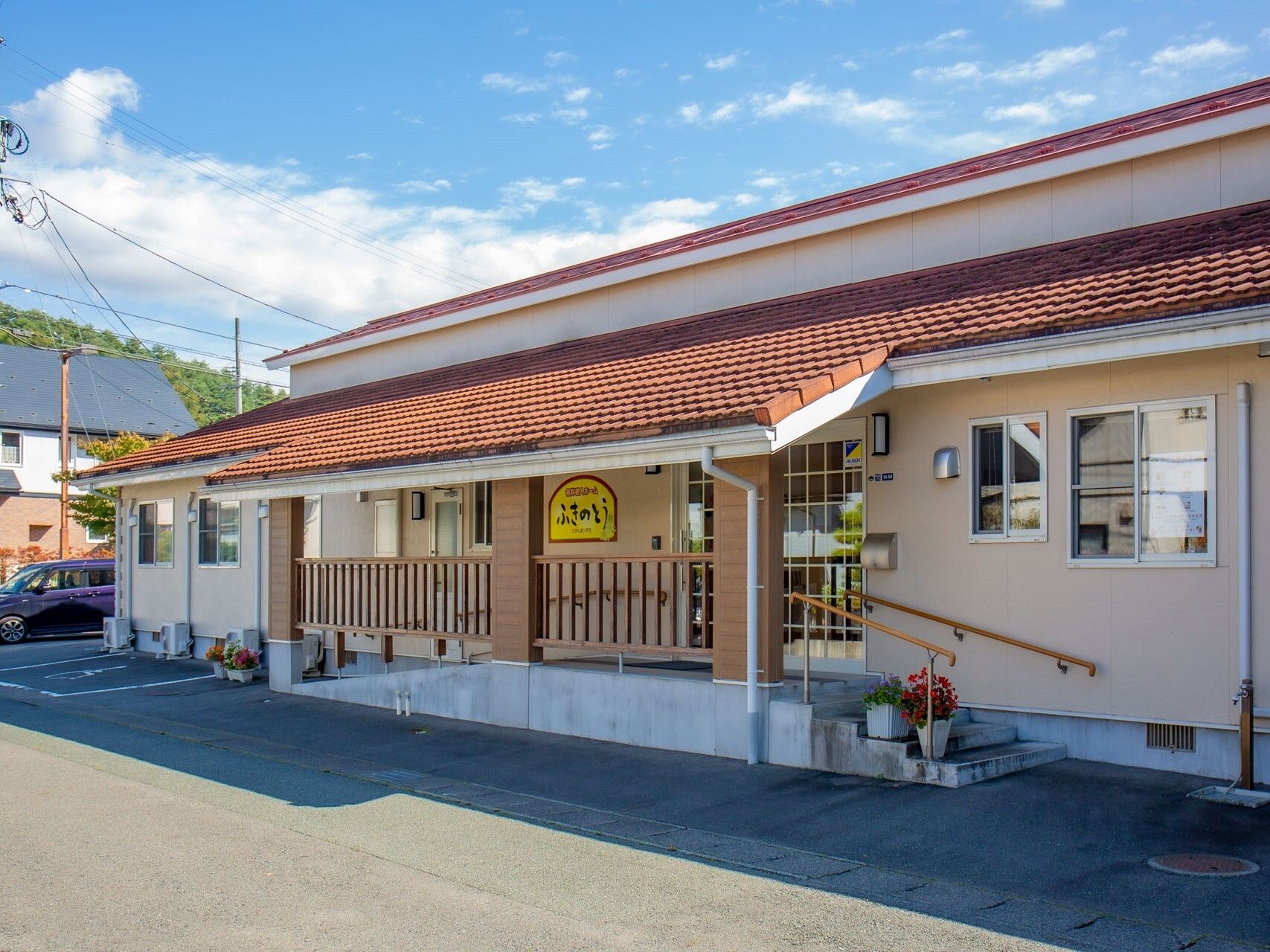 日当たりのいい場所に建っている平屋建ての建物の玄関先には手すり付きのスロープと階段が付いている。