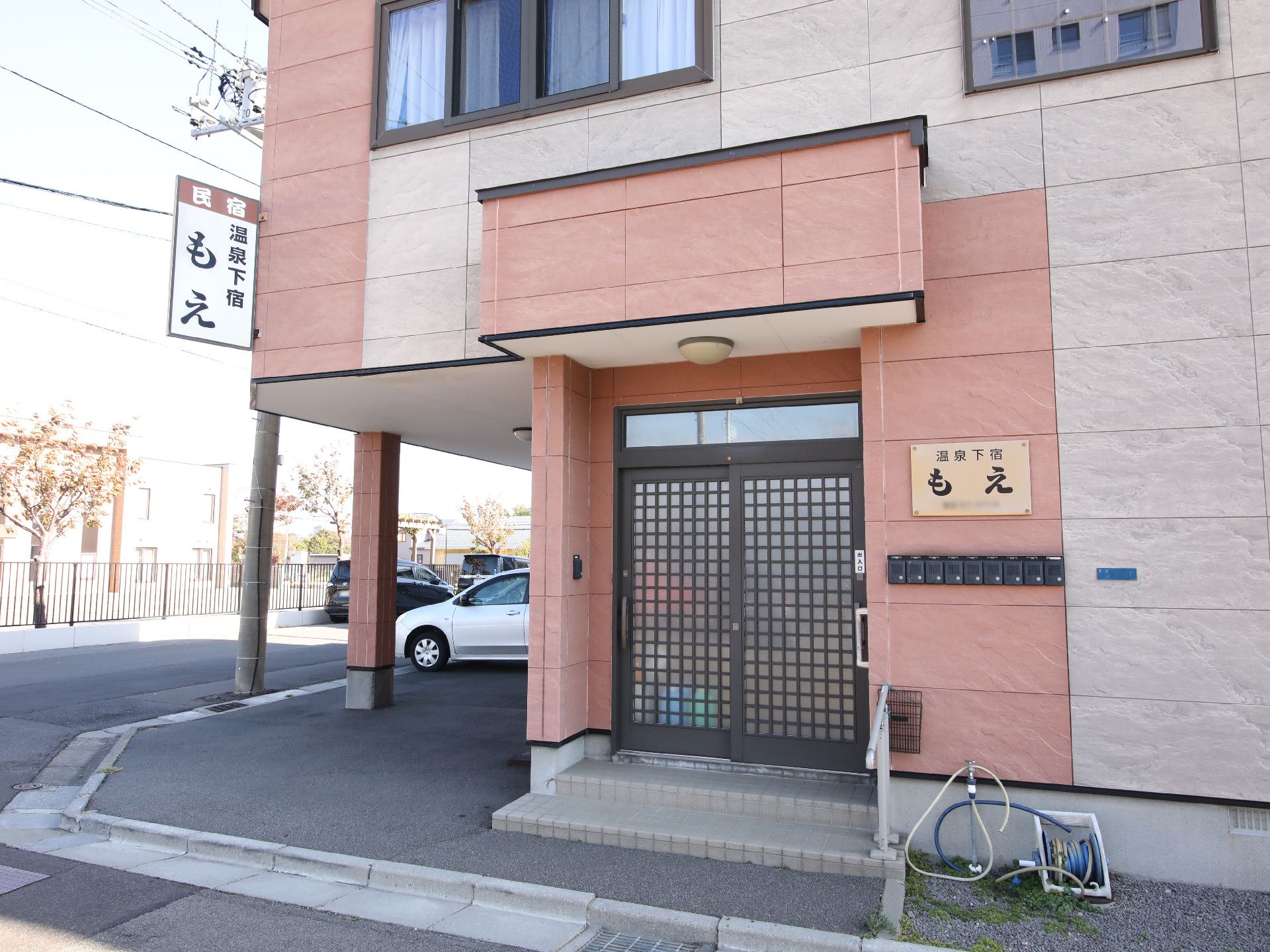 シャツを着た車いすの高齢男性とポロシャツを着た女性スタッフが一緒に屋外で過ごしている。