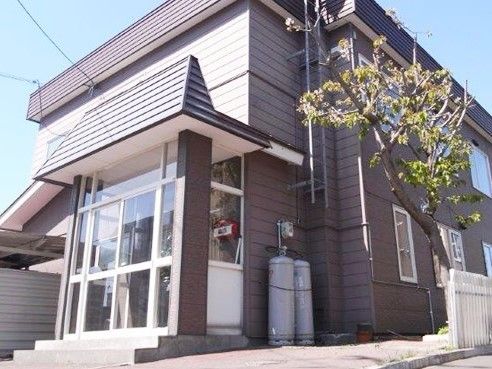 ブラウン系でまとめられた落ち着いた雰囲気の2階建ての建物。エントランスには階段がある。