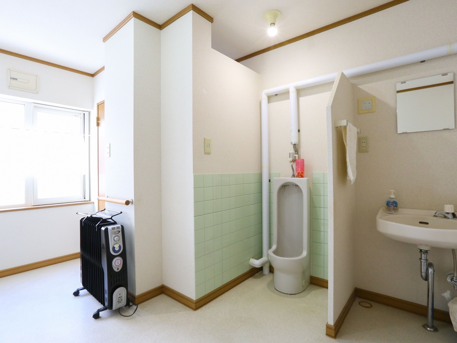 窓から日の光が白い壁に反射して、個室内は明るく開放感がある。寒さ対策のため、ファンヒーターが設置されている。