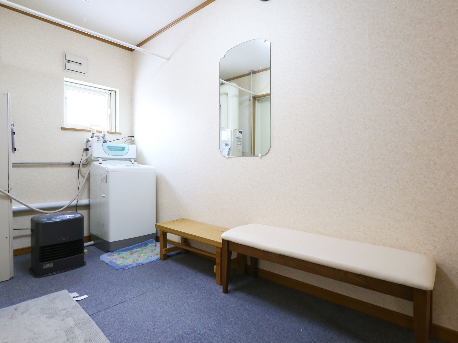 部屋の奥にある明るい窓際に、全自動洗濯機が設置されている。そばにはベンチが設置され、洗濯が終わるまで腰かけて待つことができる。