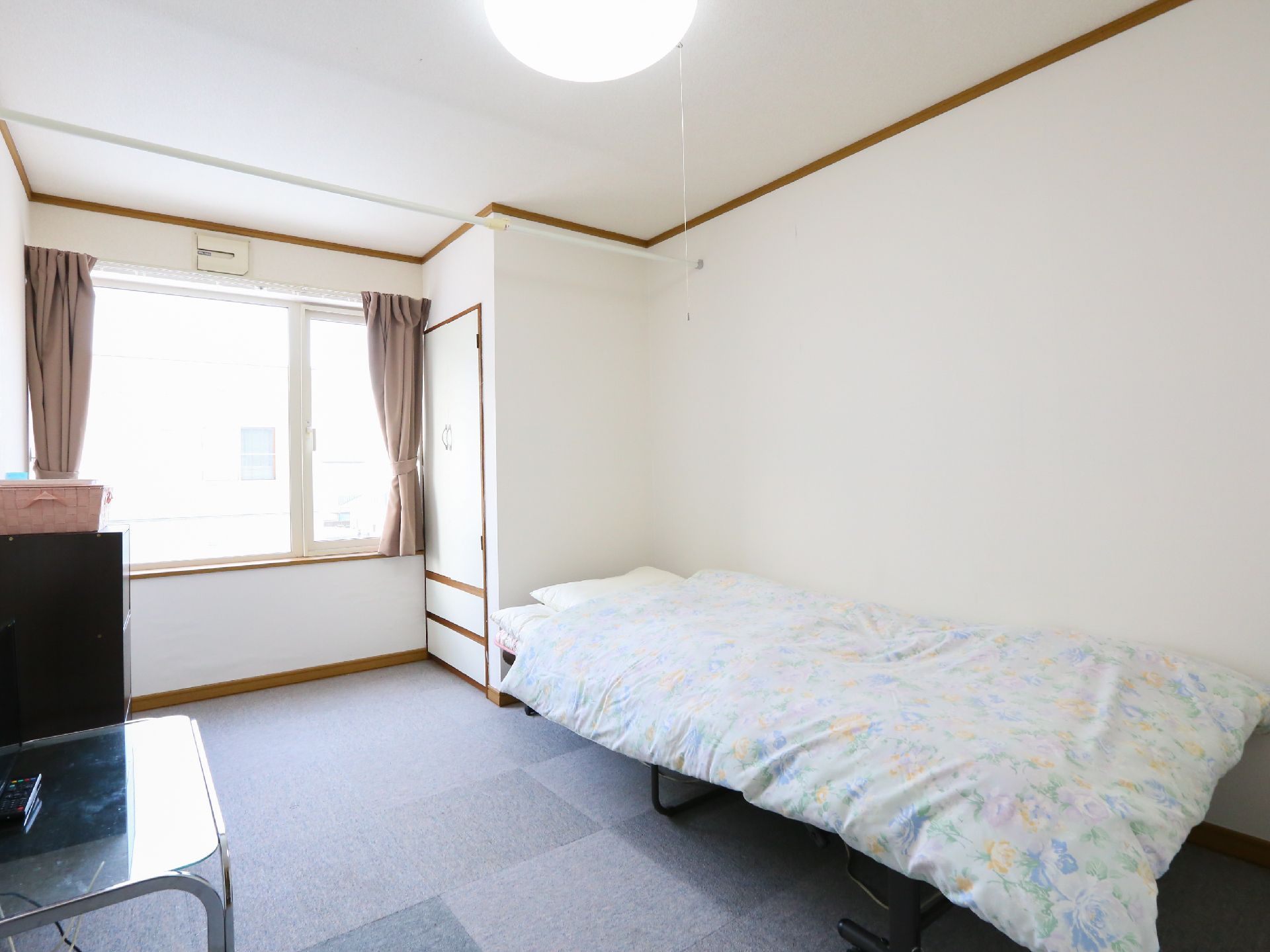 左奥に窓、その右手前に物入れ、その手前にベッドが置かれた居室