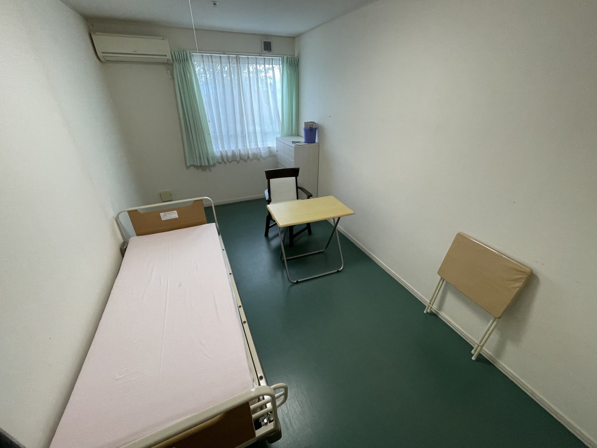 緑に囲まれた遊歩道で散歩を楽しむ車いすの入居者と女性スタッフ。