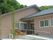 三角屋根が付いたブラウン系の平屋建ての建物はぬくもりのある雰囲気で、玄関の周りには花が植えられたプランターがある。