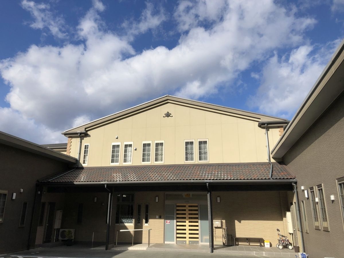 ベージュの壁にブラウンのひさしの付いた玄関のある2階建ての建物