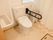 白いトイレに黒い手すりが設置されている