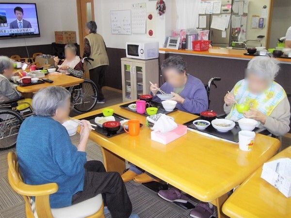 紙を貼るレクリエーションをする高齢女性と指導をする女性スタッフ