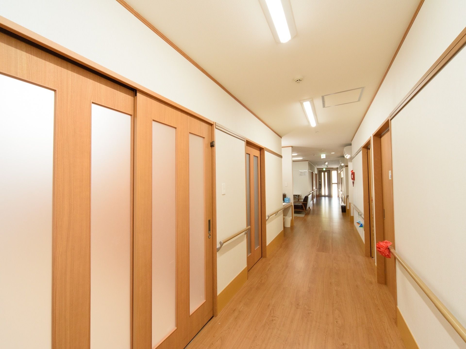 廊下は昼夜を問わず照明で明るく照らされ、利用しやすい雰囲気。居室のドアはスライド式で、開閉がしやすく間口も広い。