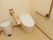 落ち着いた色合いの内装のトイレには、タンクレストイレが設置されている。周囲には安全バーや手すりなどが補助として取り付けてある。
