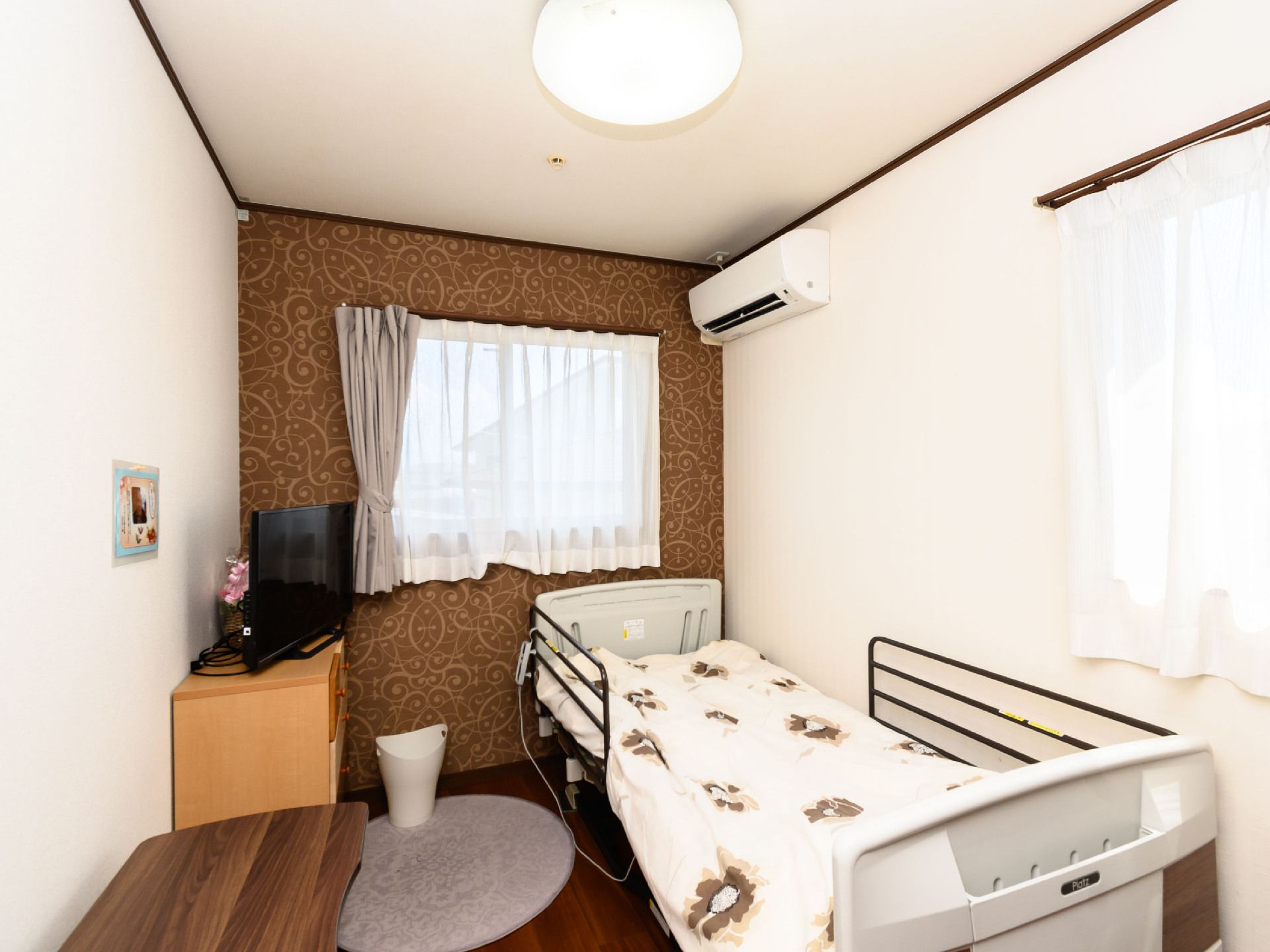 白いベッドと木製の棚が置かれた白い壁の部屋