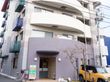 6階建のマンションのような建物である。エントランスの前は駐車場で自転車も停めることができる。植え込みには花が咲いている。