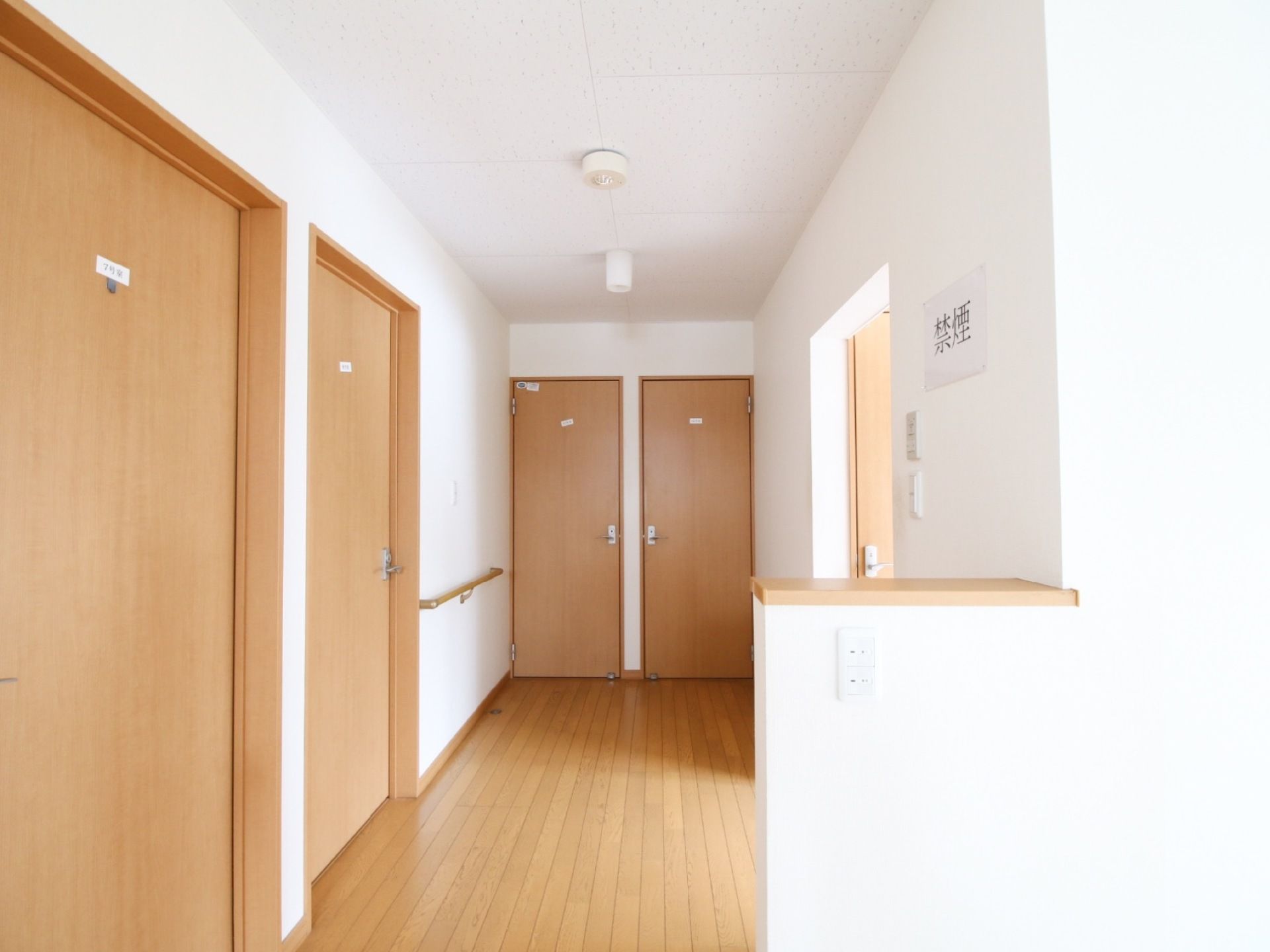 真っ白な壁が美しい通路である。手すりが完備されていて、つかまって安全に移動ができる。禁煙を徹底する張り紙がある。