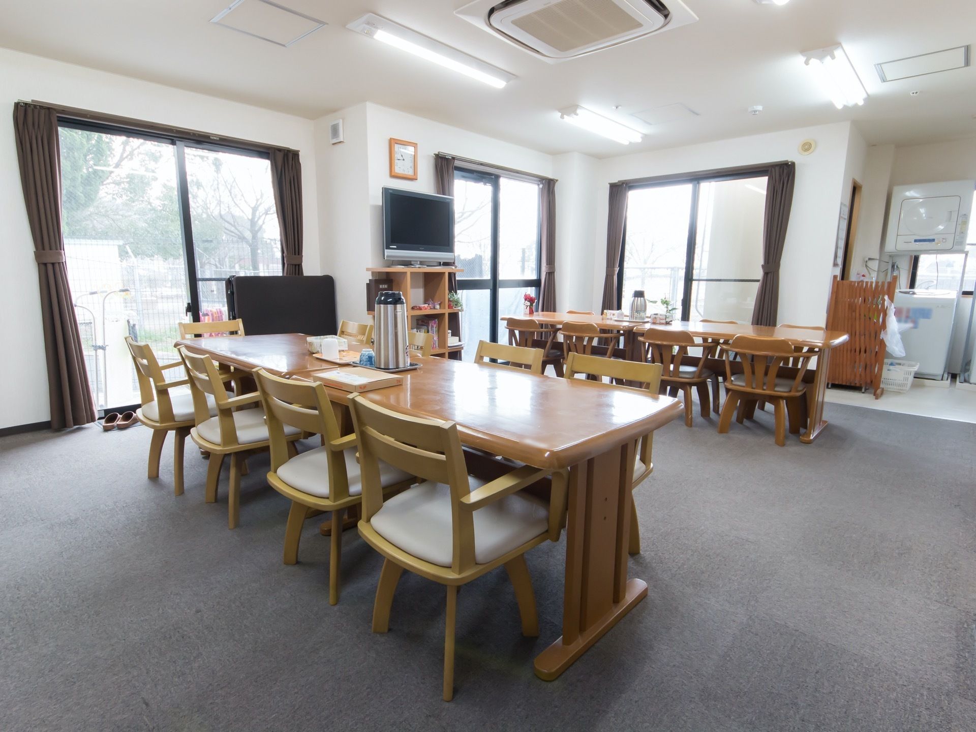 広々とした開放感のある食堂には、大型液晶テレビが完備されている。隣にはランドリースペースがあり、全自動洗濯機が置かれている。