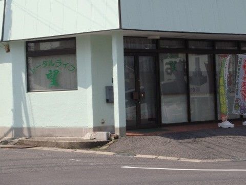 道路に面して建っている建物の玄関にはのぼりが立っていて、エントランスの窓にはホーム名が書かれている。