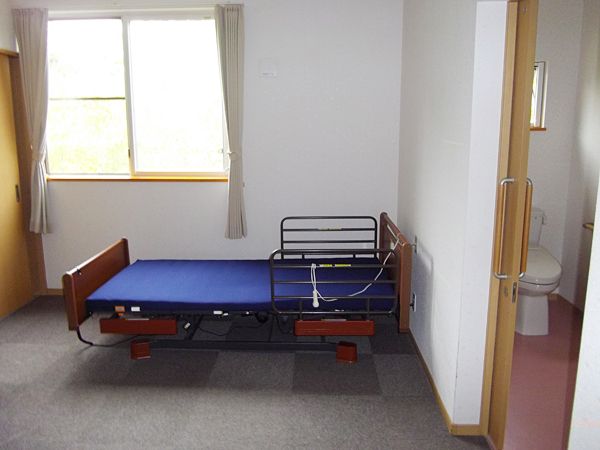 一人用の介護ベッドが置いてある小さなワンルームタイプの部屋